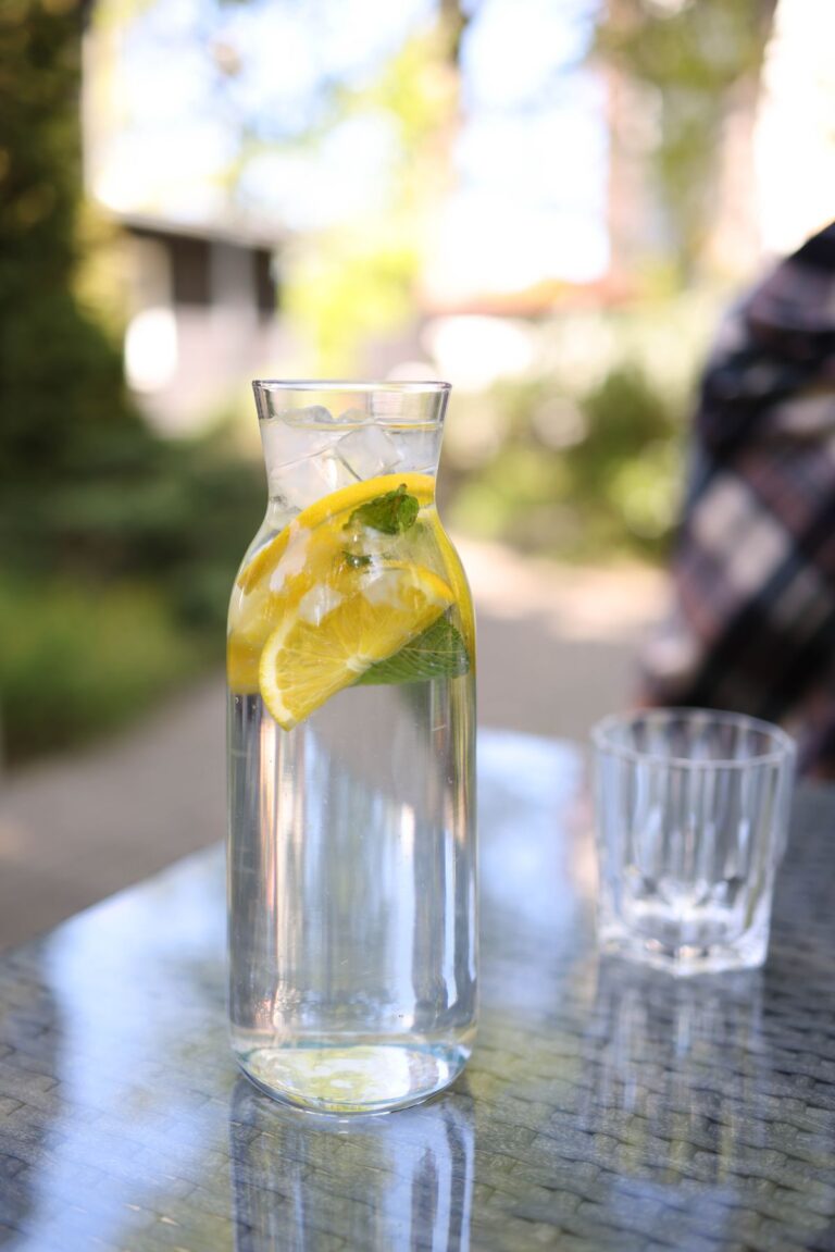 Carafe d'eau fraîche infusée au citron et à la menthe sur une table de jardin en été