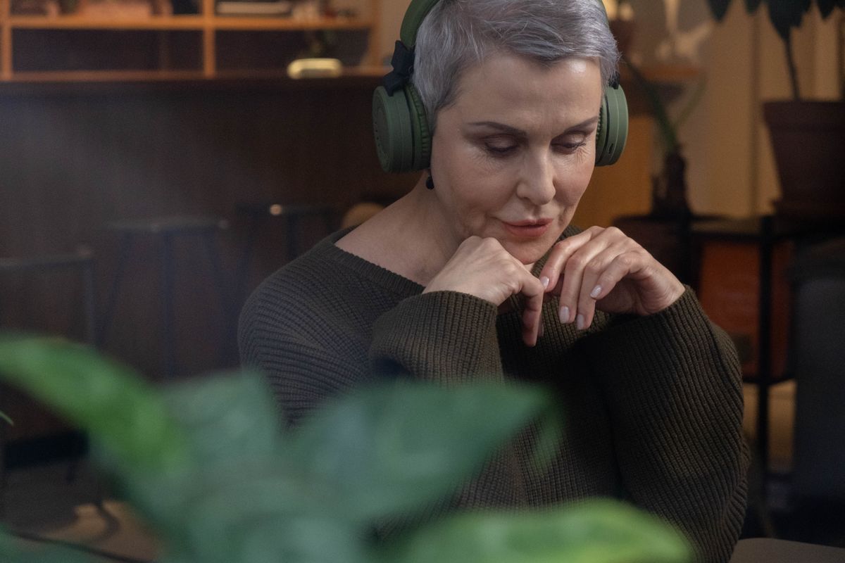 Femme senior écoutant confortablement avec un casque sans fil à domicile