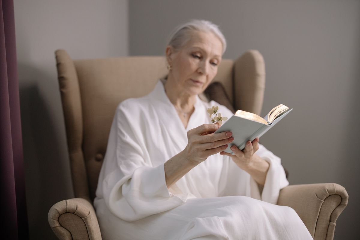 Personne âgée installée confortablement dans un fauteuil adapté, un livre à la main