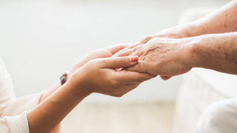 Main d'une aidante tenant la main d'une personne âgée — syndrome de glissement