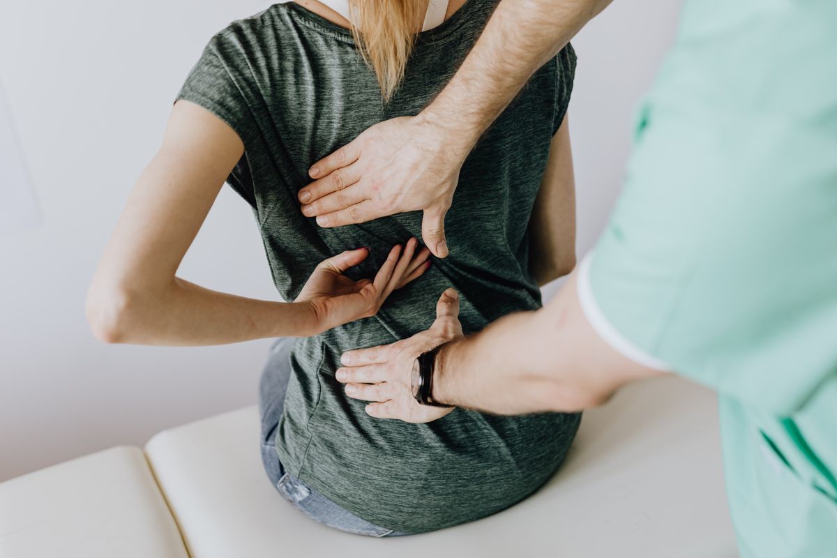 Femme souffrant du bas du dos, examinée par un professionnel de santé