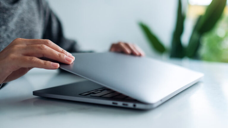 Mains fermant un ordinateur portable en fin de journée