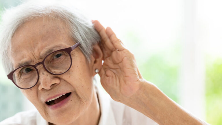 Femme âgée mettant la main derrière l'oreille pour entendre