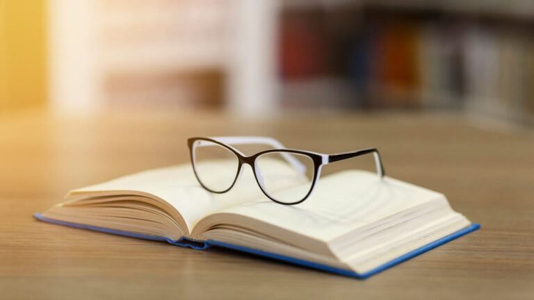 Lunettes posées sur un livre ouvert au soleil