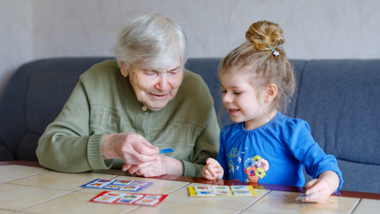 Grand-mère jouant à un jeu de cartes mémoire avec une petite fille