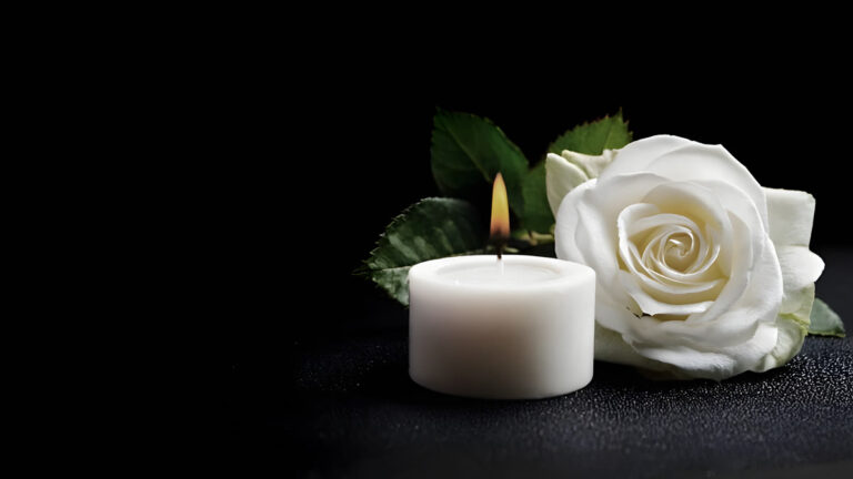 Bougie funéraire et rose blanche sur fond sombre