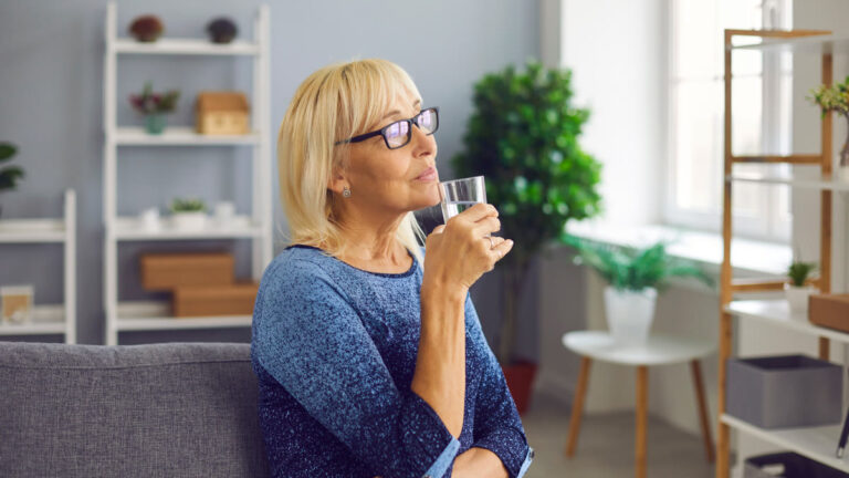Femme âgée buvant un grand verre d'eau