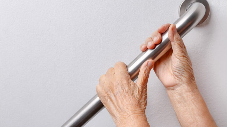 Main d'une personne âgée agrippant une rampe d'escalier