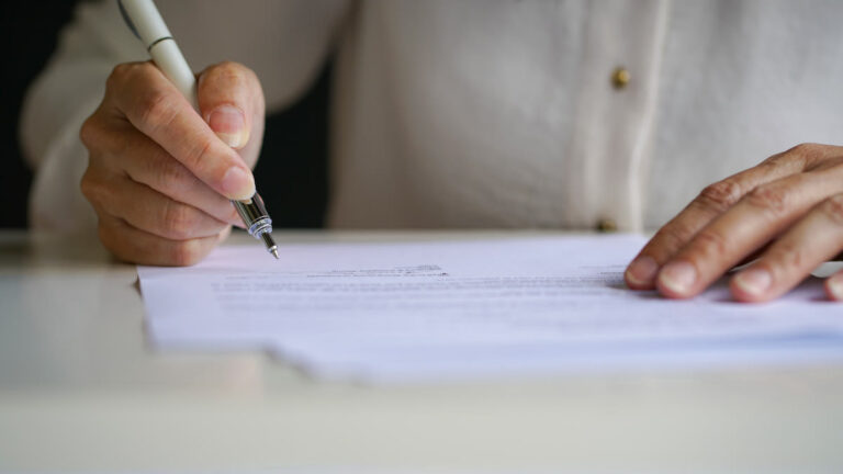 Main signant un document officiel au stylo