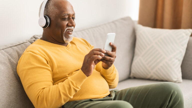 Homme mûr souriant portant un casque audio chez lui