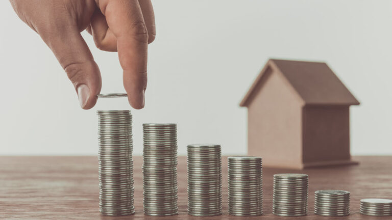 Petite maison et pièces empilées sur une table — patrimoine