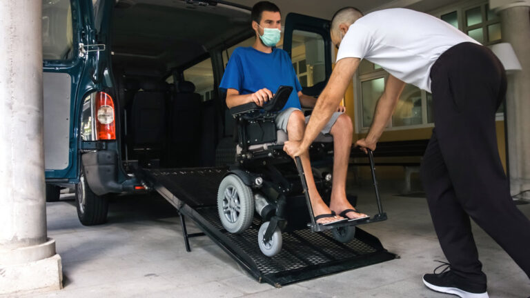 Homme en fauteuil roulant montant dans un véhicule adapté avec rampe