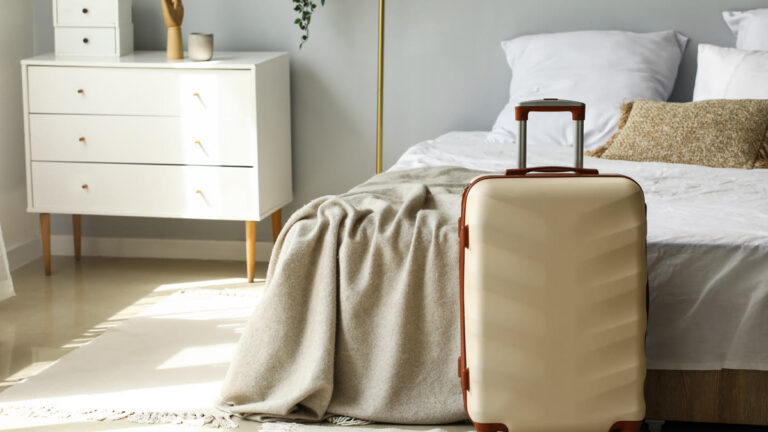 Valise prête posée près d'un lit dans une chambre lumineuse