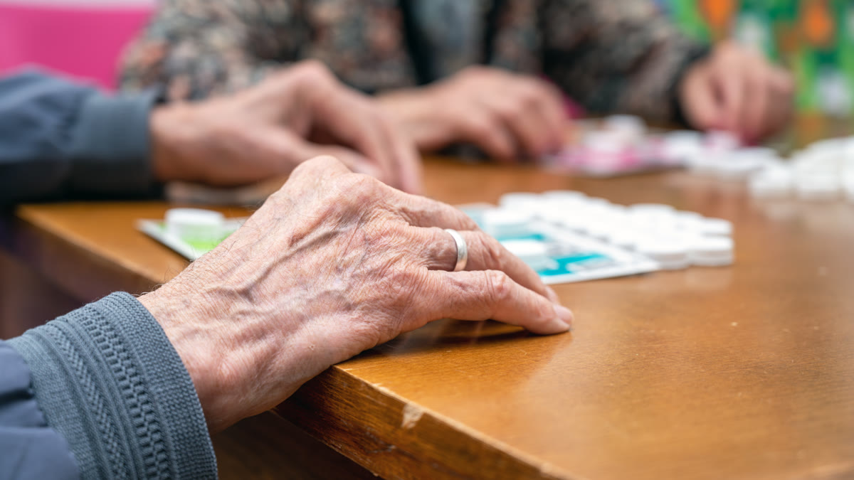 Mains de seniors jouant ensemble autour d'une table