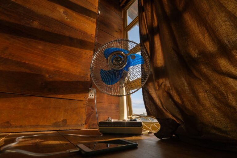 Ventilateur devant une fenêtre entrouverte pour rafraîchir une chambre sans climatisation
