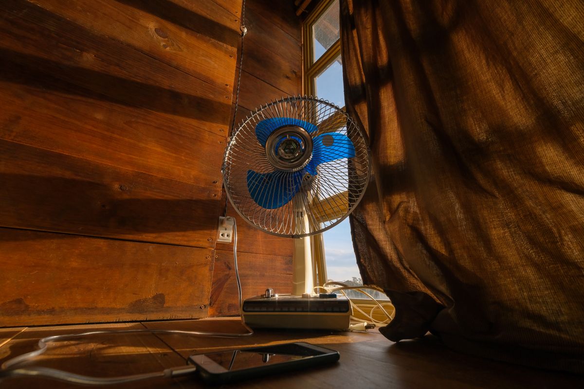 Ventilateur devant une fenêtre entrouverte pour rafraîchir une chambre sans climatisation
