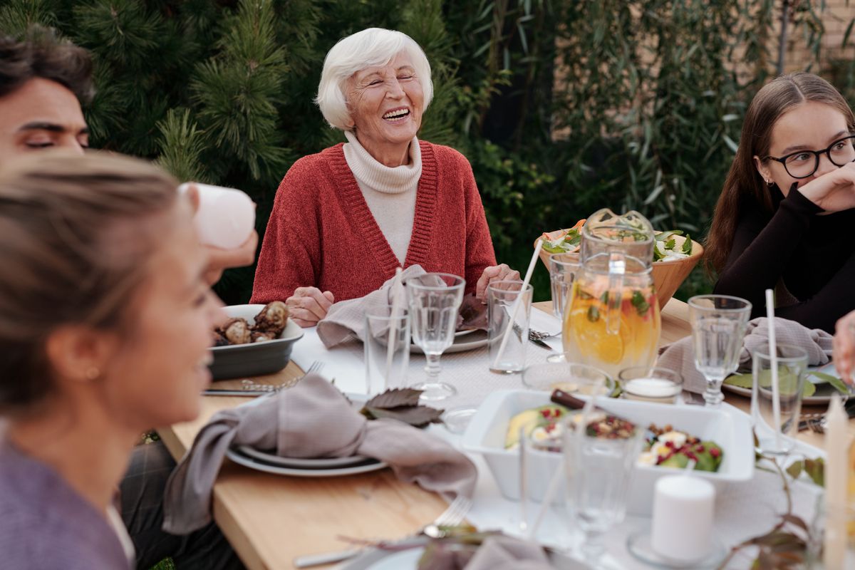 Repas en famille au jardin avec une personne âgée souriante