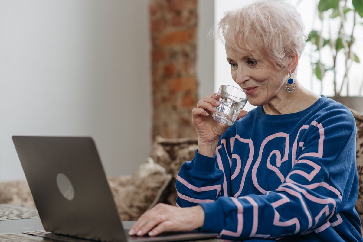Femme âgée buvant un verre d'eau à son domicile