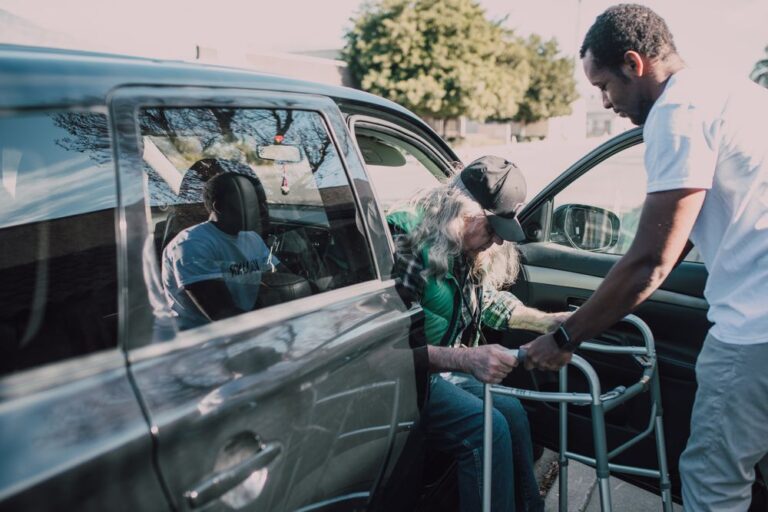 Aidant aidant une personne âgée avec un déambulateur à monter en voiture pour un rendez-vous médical