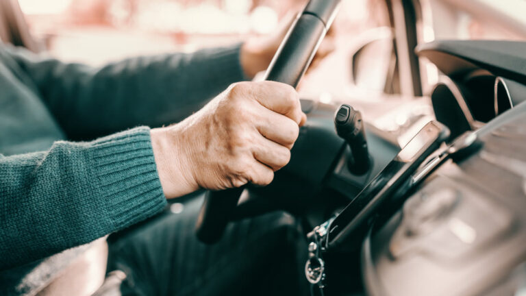Mains d'un conducteur senior sur le volant