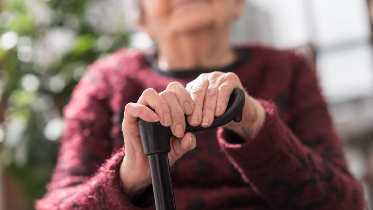 Mains d'une personne âgée posées sur une canne