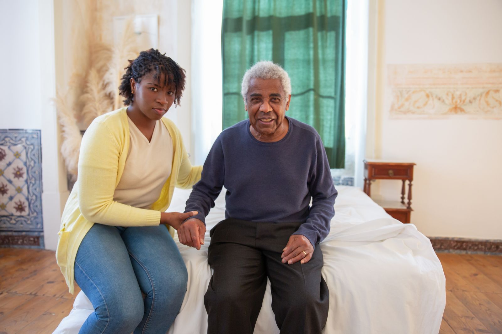 Aidante assise près d'un homme âgé, main dans la main, accompagnement Alzheimer