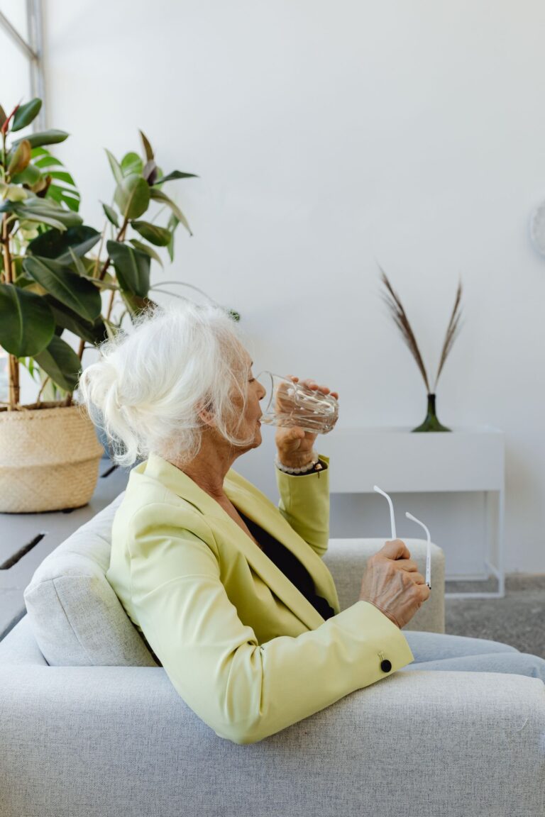 Femme âgée buvant un verre d'eau, prévention de la déshydratation