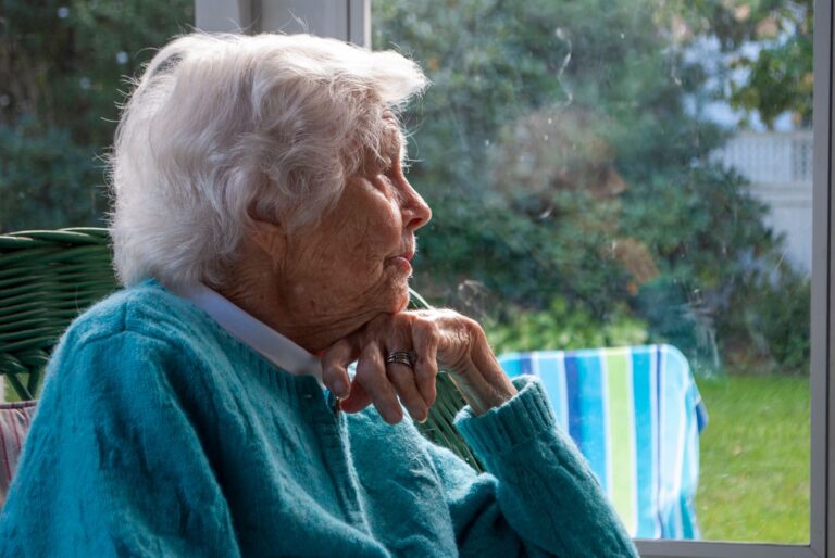 Femme âgée pensive regardant par la fenêtre