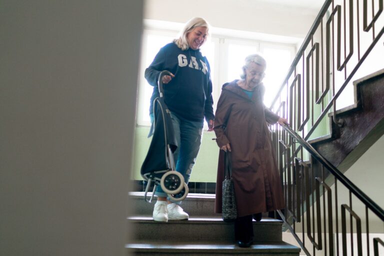 Femme âgée descendant un escalier en se tenant à la rampe, prévention des chutes
