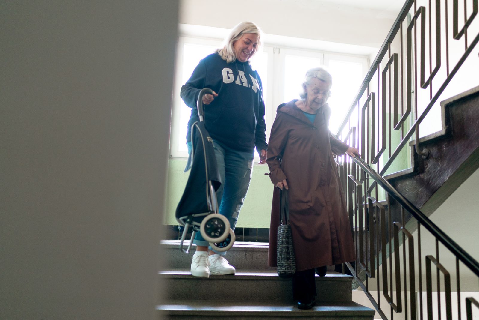 Femme âgée descendant un escalier en se tenant à la rampe, prévention des chutes