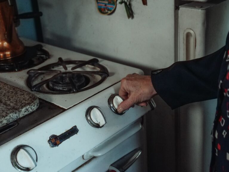 Main tournant le bouton d'une gazinière, sécuriser la cuisine d'une personne âgée