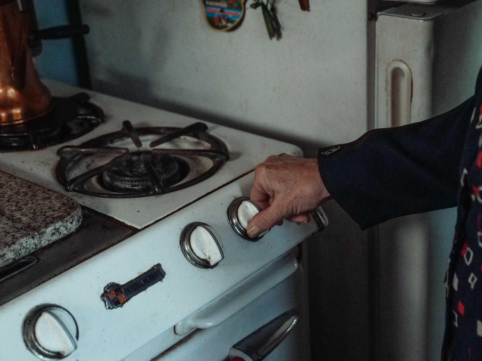 Main tournant le bouton d'une gazinière, sécuriser la cuisine d'une personne âgée