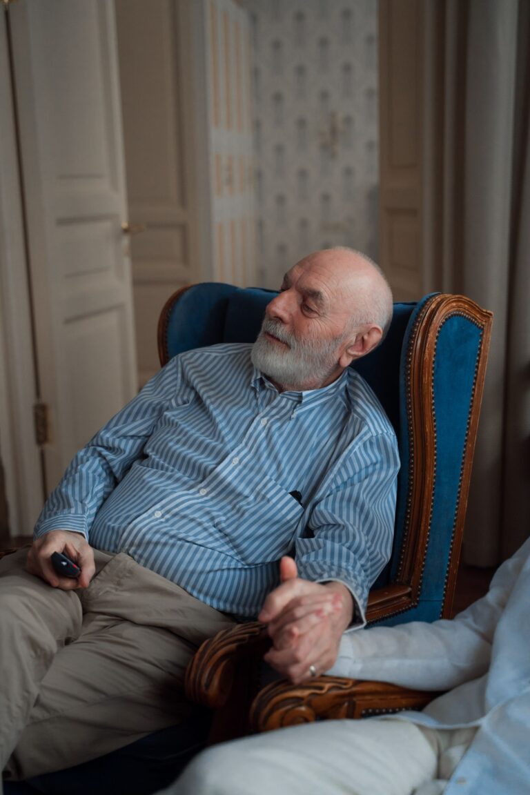 Homme âgé installé dans son fauteuil, télécommande à la main