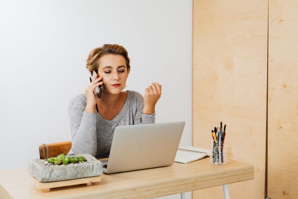 Femme au téléphone devant son ordinateur, entre travail et appels pour un proche