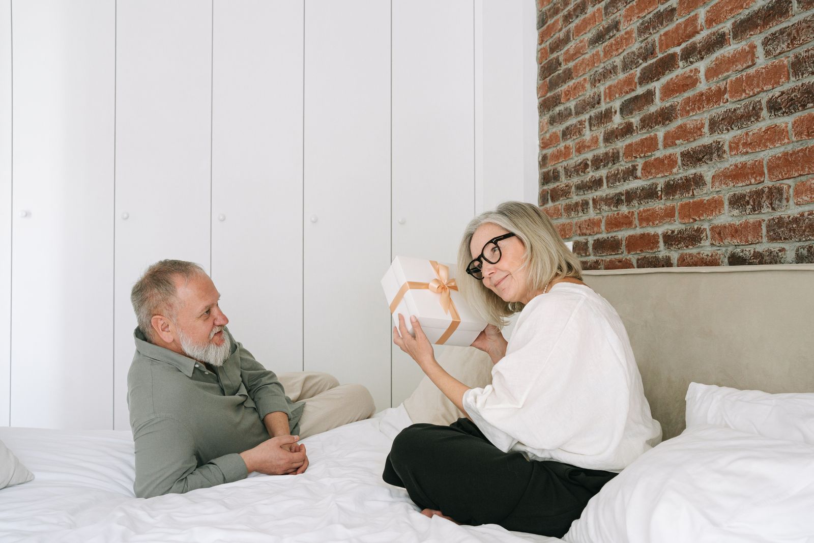 Couple âgé échangeant un cadeau dans une chambre confortable