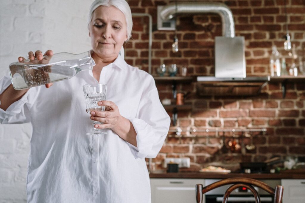 Femme âgée se servant un verre d'eau dans sa cuisine