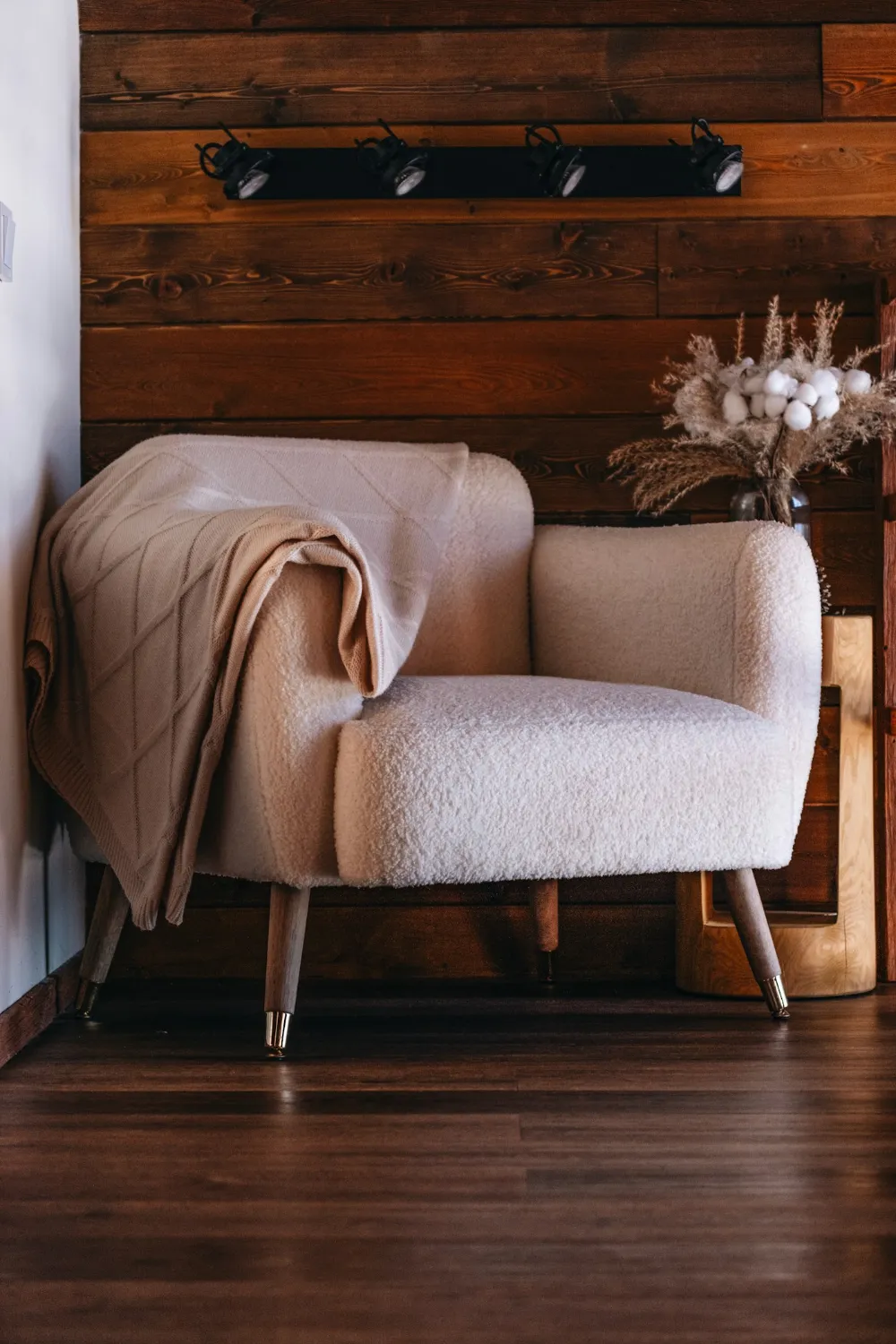 Fauteuil clair avec un plaid posé sur l'accoudoir, dans un salon calme