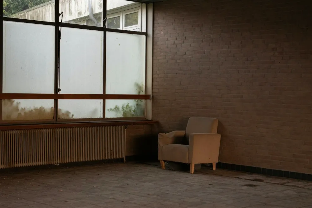 Fauteuil vide près d'une grande fenêtre dans une pièce silencieuse