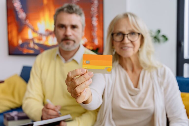 Couple âgé tenant une carte bancaire dans son salon