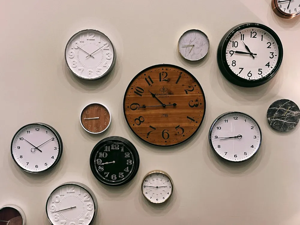 Plusieurs horloges murales accrochées sur un mur clair