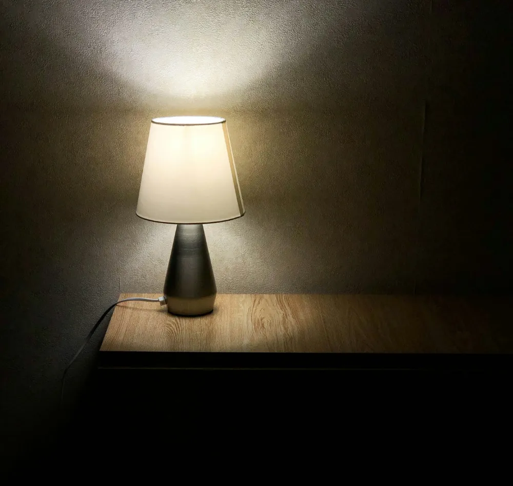 Lampe de chevet allumée dans une chambre plongée dans la pénombre