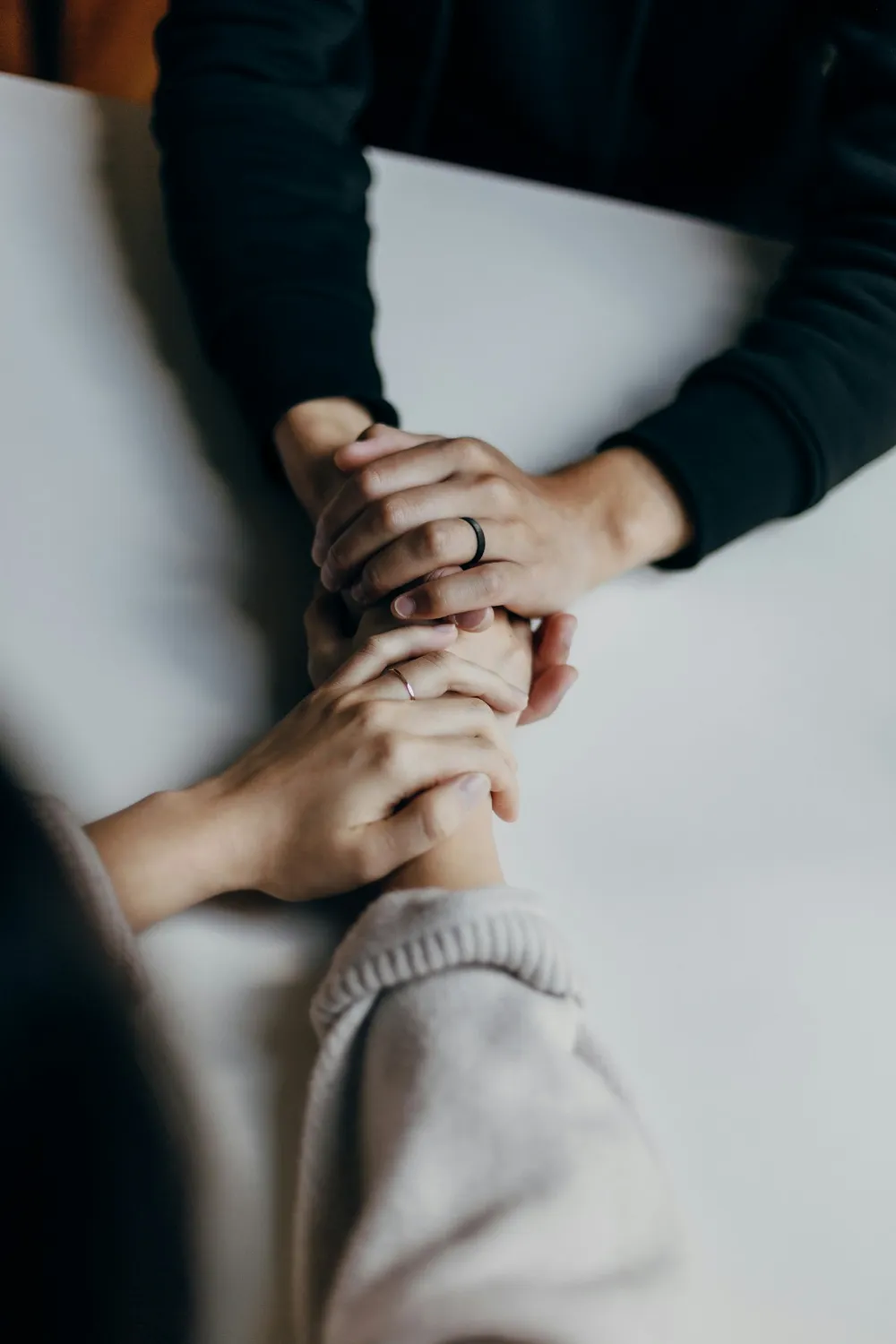 Deux personnes se tenant les mains sur une table en signe de réconfort