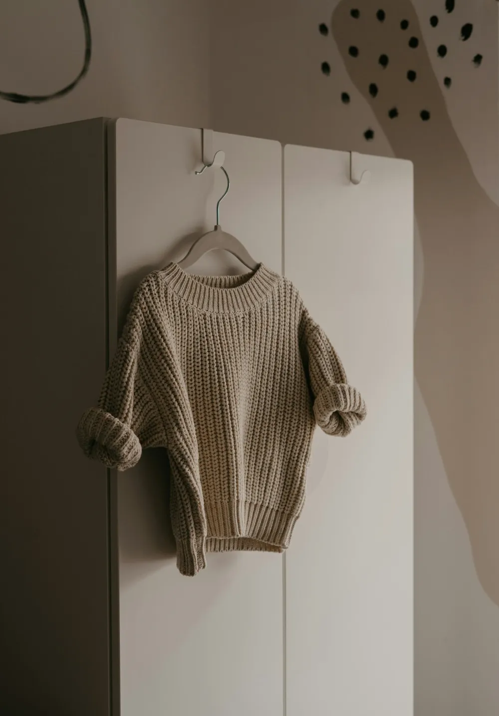 Pull en grosse maille beige suspendu à un cintre