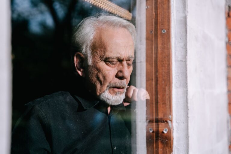 Homme âgé pensif devant une fenêtre ensoleillée